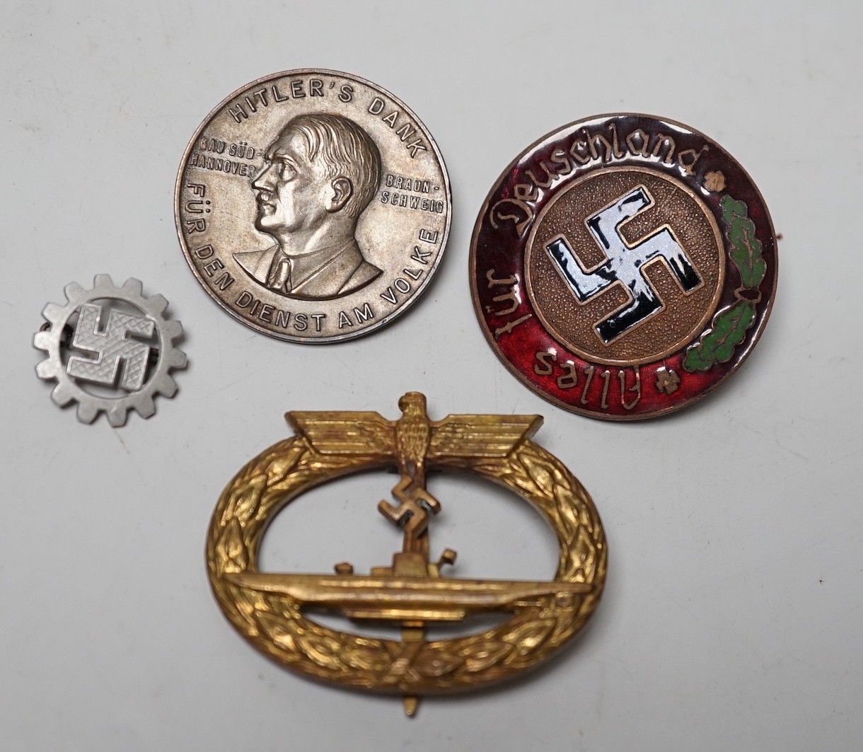 Four German WWII badges including a Kriegsmarine submarine war badge, maker’s mark Frank and Reif Stuttgart